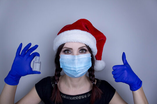 Woman wearing protection face mask against coronavirus. Woman in a mask and Christmas hat with sanitizer. Funny Christmas accessory. Medical mask, Close up shot, Select focus, Prevention from covid19
