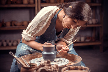 Charming handicraftsman creates a new pottery from clay on a potter's wheel. Pottery workshop.
