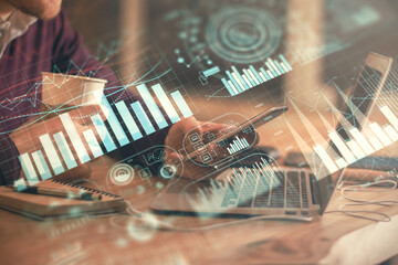 Double exposure of man's hands holding and using a phone and financial graph drawing. Analysis concept.