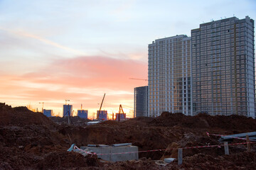 View on the large construction site with tower cranes and buildings on sunset background.  Excavation and earthworks for infrastructure improvement. Sewerage and communications laying