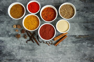 Aromatic spices in white bowls on a wooden table - saffron,  vanilla,  sumac and star anise. Fragrant seasonings.