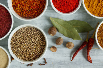 Aromatic spices in white bowls on a wooden table - saffron,  vanilla,  sumac and star anise. Fragrant seasonings.
