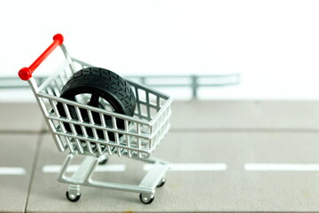 Miniature shopping cart model containing wheel of model car scene represent car part online shopping concept related idea.