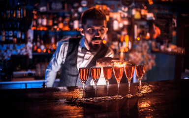 Charismatic bartending pouring fresh alcoholic drink into the glasses behind the bar