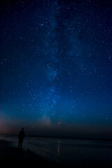 Adventurous man watching the stars on a beach at night.  - obrazy, fototapety, plakaty