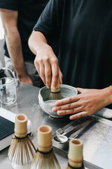 Making japanese iced matcha latte, tea is whipped with a bamboo whisk, traditional matcha tools.