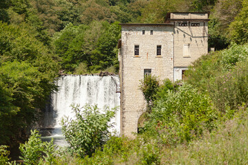 Obraz premium Old abandoned hydroelectric power plant against a backdrop of green trees
