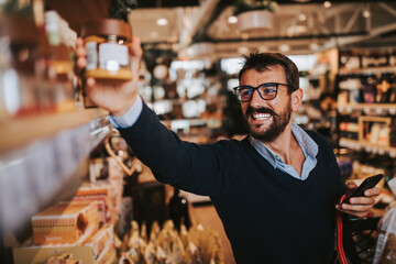 Handsome middle age man buying some healthy food and drink in modern supermarket or grocery store....