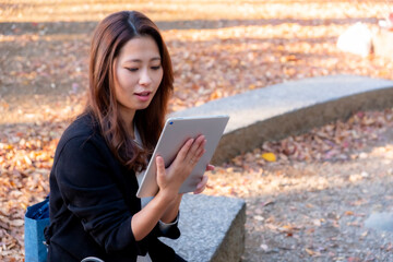 Obraz premium 【東京都】屋外でタブレットを操作する女性【2020年 紅葉】