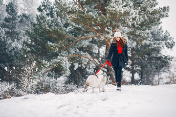 Cute girl in a winter park. Woman palying with a dog. Lady in a black jacket