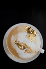 Cup of cappuccino with a golden foam, luxury drink concept