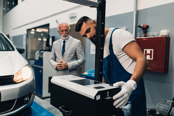 Car mechanic talking with senior business man costumer during periodic car condition check. Technical inspection.