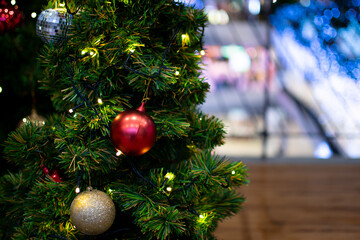 The green Christmas tree decorated with small bulbs is a beautiful bokeh. Christmas tree decoration with white, red, golden balls, Close-up a photo, copy space for design, blurred wooden background.