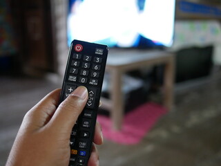 closeup of hand with the remote control television and presses the button.