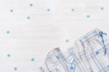 Folded warm white pajamas with blue checks or stripes. Sleepwear for night time decorated snowflakes for winter holiday.