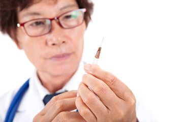 A Chinese doctor in a white coat in front of a white background is preparing to give a patient an injection