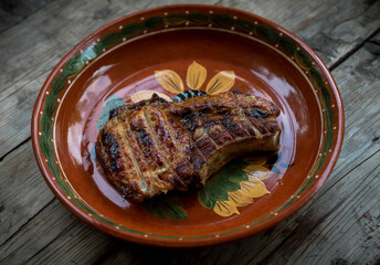 Hot grilled meat in plate on the rustic background. Selective focus.
