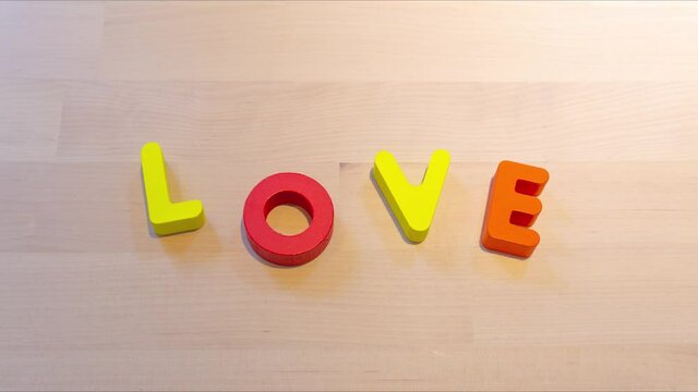 Love text stop motion animation on wood desk, jumping words for love concept. Valentine's Day social media footage. Love and relationship concept creative footage. Seamless looping video for lovers