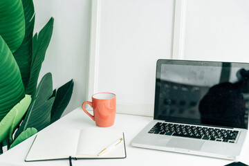 Minimal workspace with coffee cup and laptop and book.