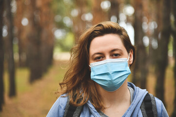 Young woman wearing in a protective mask in a park. Quarantine, anti coronavirus, virus and flu concept.