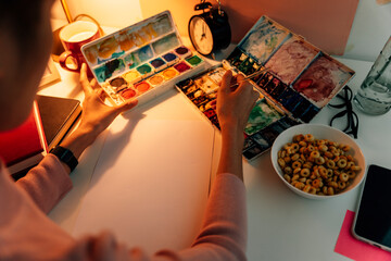 Painting artist working on new art at workshop space in evening time.