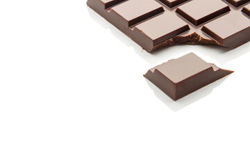 Fragment of a bar of natural dark chocolate on a white background. Copy space