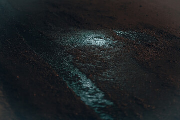 Asphalt at night. Puddle and light spot on the night road