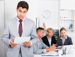 Angry manager standing in office dissatisfied with teamwork of colleagues