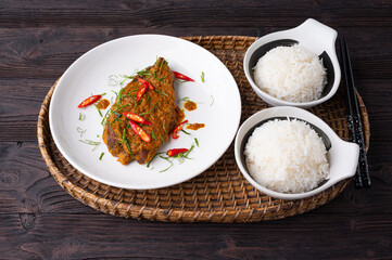 Close up view of Spicy Red Curry with crispy fried fish,  on white dish