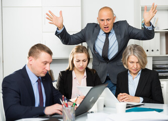Irritated boss scolding group of stressed managers for incompetence at meeting in office. High quality photo