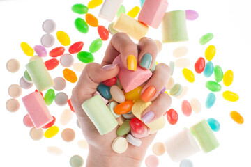 Hand holding assorted candies with colored nails 