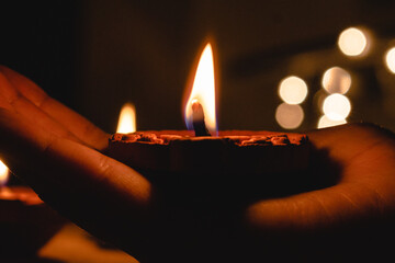 Happy Diwali - Hand holding Diya clay lamp in the dark backgrounds. In celebration of Indian festival Diwali	
