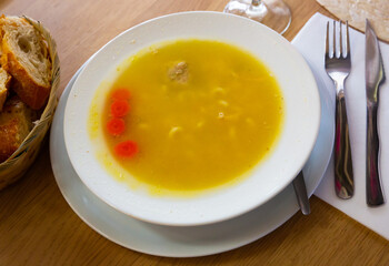 Traditional Catalan meat and vegetable soup Escudella in white plate