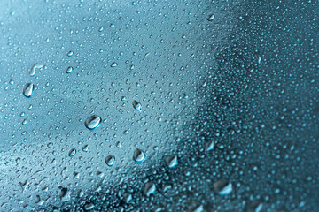 Abstract background with raindrops and beautiful blue bokeh. The concept of autumn and the cold stormy weather. Texture of macro drops on the blurred background of the window. Loneliness sadness