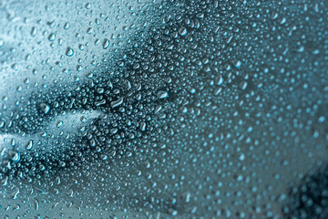 Abstract background with raindrops and beautiful blue bokeh. The concept of autumn and the cold stormy weather. Texture of macro drops on the blurred background of the window. Loneliness sadness