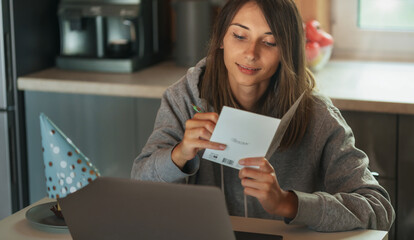 Woman signs a holiday card for birthday. Online celebration