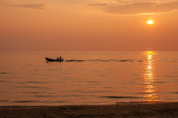 Naklejka na ściany i meble Sunset at the beach and fishing boats pass by