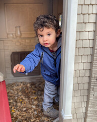 Moroccan toddler boy playing outside in play house.