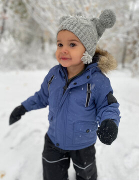 Cute Moroccan toddler walking through first snow while hiking.