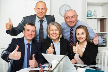 Happy adult team of business people emotionally gesturing and celebrating in office. High quality photo