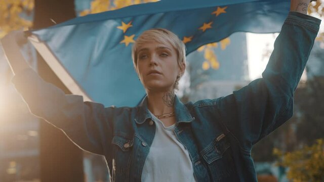 Young caucasian woman spinning in the park with the flag of european union. High quality 4k footage