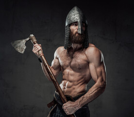 Brutal and muscular northern marauder posing with his two handed axe in dark custom background.