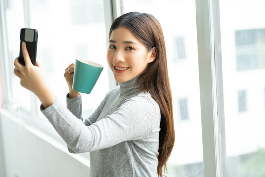 Asian Business Woman Standing Taking Selfie Photo By Window
