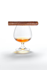 Closed up view of glass of whiskey with cigar on top on white back