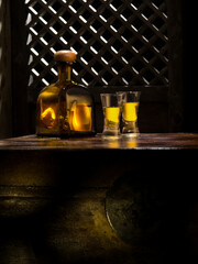 Close up view of bottle of tequila anejo and glasses on color background