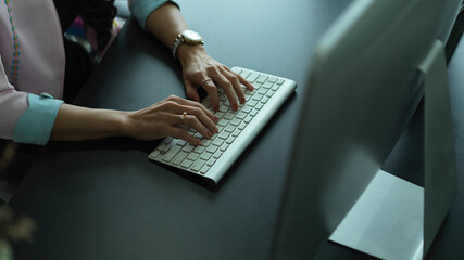 Female hands typing on wireless computer keyboard on office desk