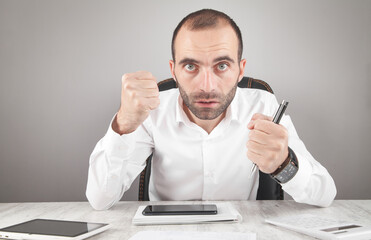 Caucasian angry man looking in camera threatening with fists.