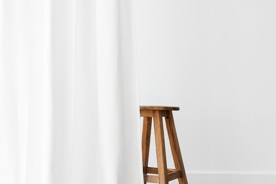 Wooden stool behind a white curtain