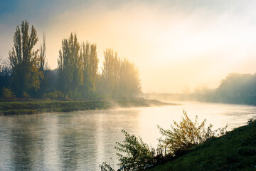 misty morning sunrise on the river. beautiful autumnal scenery with glowing sky. bridge in the distance. pravoslavna embankment of uzhgorod, ukraine