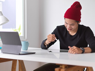 Close up view of young man working with digital tablet on white table